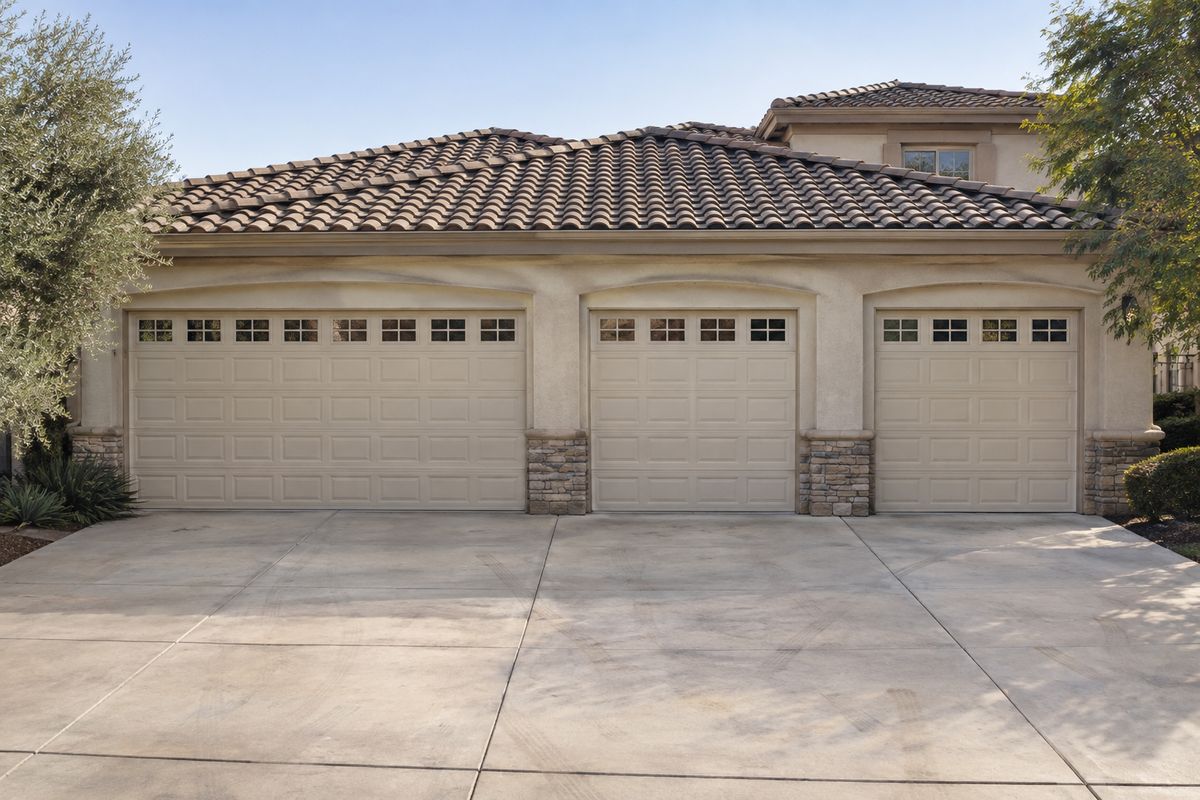 Three garage doors with window rows across the front of a tile-roofed home