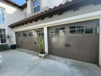 Two bronze carriage-house garage doors with decorative handles on a Spanish-style home in Orange