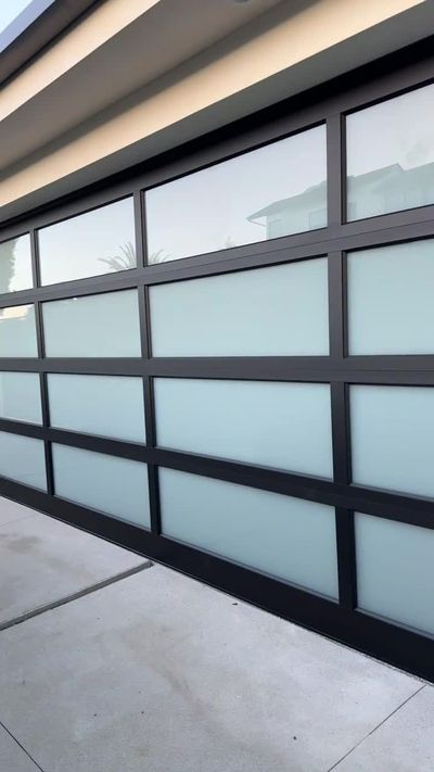 Close view of a full-view garage door with a black aluminum frame and frosted glass panels in Orange County