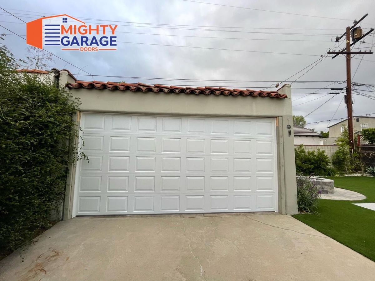White raised-panel double garage door on a single-story Anaheim home with a red tile roof