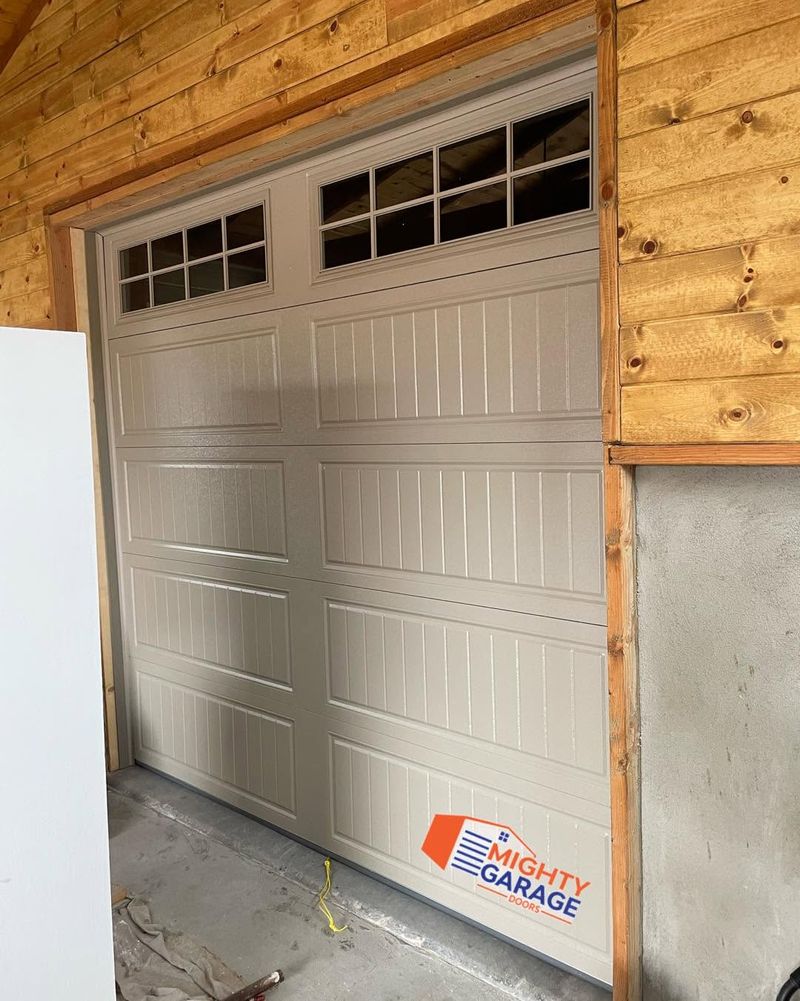 Almond raised-panel garage door with a row of square windows, installed in a wood-framed opening in Anaheim