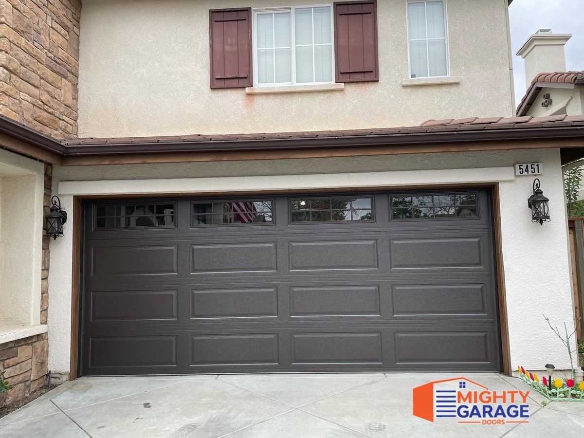 Dark brown long-panel double garage door on a two-story Anaheim home with stone veneer and shutters