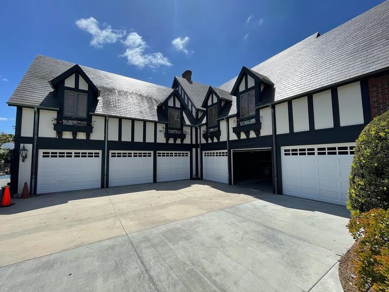 Several white garage doors along a Tudor-style building in Orange with dark timber detailing and a shared driveway