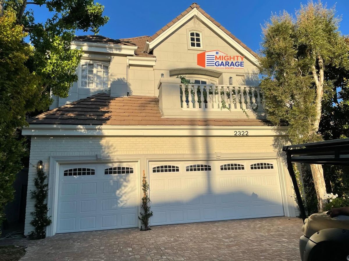 Cream double garage door and two single doors with window rows on a two-story Mediterranean home in Orange County