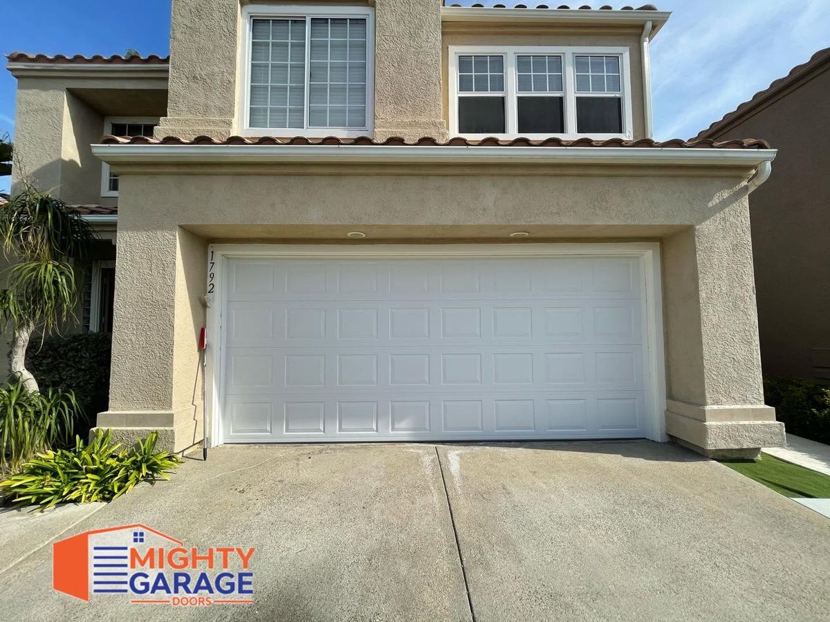 White raised-panel double garage door on a two-story stucco home with a tile roof in Riverside